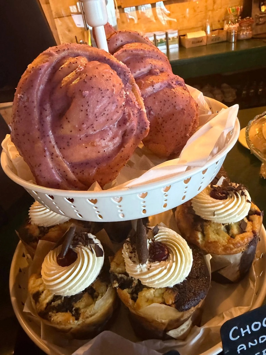 A cake stand of iced swirl buns and cherry-topped marble muffins on the caf&eacute; counter